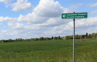 Das Foto zeigt den Wegweiser mit der Aufschrift: Geografischer Mittelpunkt des Landes Brandenburg.